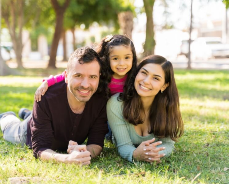 Family lying in the park grass and smiling